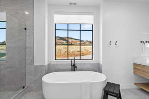 Bathroom featuring vanity, a freestanding bath, walk in shower, tile walls, and a mountain view