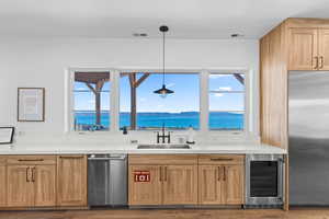 Kitchen with stainless steel appliances, wine cooler, light brown cabinets, a water view, and wood finished floors