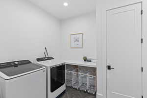Washroom with dark tile patterned flooring, washer and clothes dryer, and recessed lighting