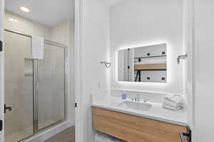 Bathroom with a shower stall, vanity, light tile patterned flooring, and recessed lighting