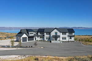 View of front of home featuring a garage, board and batten siding, roof mounted solar panels, driveway, and a metal roof