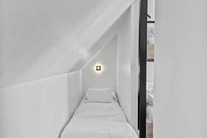 Bedroom featuring a textured ceiling, vaulted ceiling, and wood finished floors