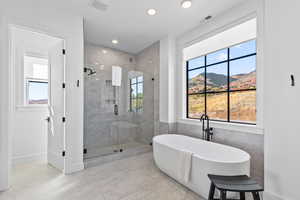 Full bath featuring a freestanding tub, a shower stall, a mountain view, tile walls, and recessed lighting