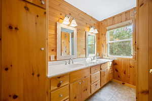 Bathroom featuring wooden walls, double vanity, and light tile patterned floors