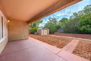 Fenced backyard featuring a shed and a patio