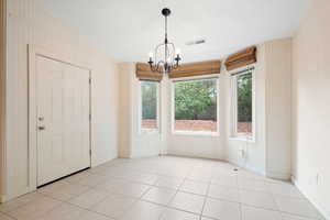 Unfurnished dining area with plenty of natural light, light tile patterned floors, and a chandelier