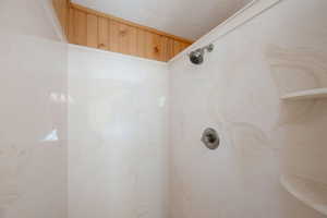 Bathroom view of a marble finish shower and a textured ceiling