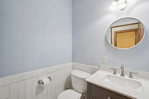 Half bathroom with wainscoting and vanity