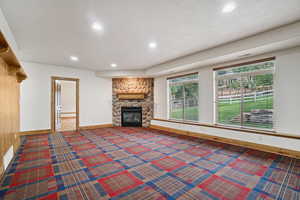 Unfurnished living room featuring a fireplace, recessed lighting, and a baseboard heating unit