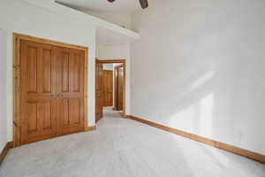 Unfurnished bedroom with carpet, a closet, ceiling fan, and a high ceiling