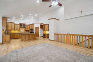 Kitchen with a kitchen island, open floor plan, light wood-style flooring, backsplash, and brown cabinetry