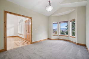 Spare room with light colored carpet, lofted ceiling, and a mountain view