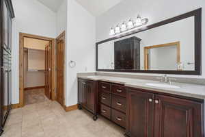 Full bath with a walk in closet, double vanity, and light tile patterned floors