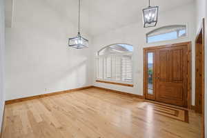 Entrance foyer featuring a chandelier, high vaulted ceiling, and light wood-style floors