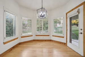 Unfurnished sunroom with hardwood / wood-style flooring and a chandelier
