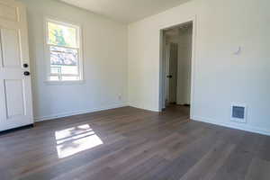 Spare room with baseboards and dark wood-style floors