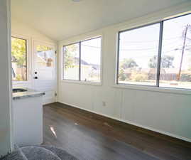 Unfurnished sunroom with wood-type flooring and lofted ceiling