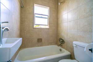Full bath featuring tub / shower combination and tile walls