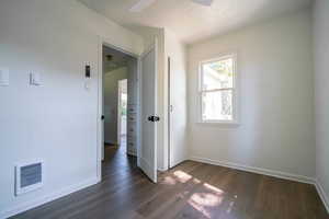 Unfurnished bedroom featuring dark wood-style floors, a textured ceiling, heating unit, and ceiling fan