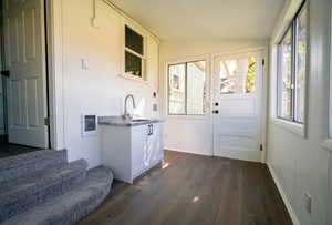 Doorway to outside with wood-type flooring and vaulted ceiling