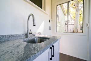 Kitchen featuring dark wood finished floors, white cabinetry, and light stone countertops