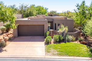 Adobe home with stucco siding, a garage, and concrete driveway