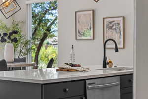 Kitchen view of gray cabinetry, dishwasher, and light stone counters