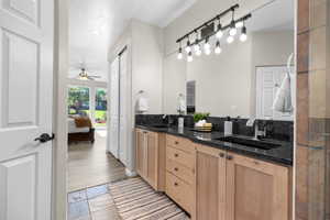 Full bath featuring double vanity, ensuite bathroom, and a ceiling fan