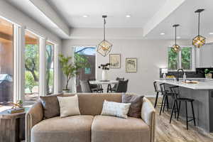 Living area with a tray ceiling, light wood-style floors, and recessed lighting