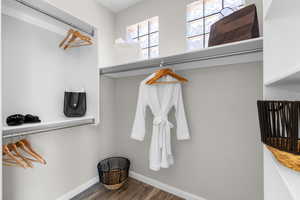 Walk in closet with dark wood-type flooring
