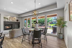 Dining space with light wood-type flooring, a stone fireplace, a chandelier, and recessed lighting