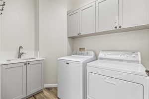 Washroom with cabinet space, washer and clothes dryer, and light wood-style floors