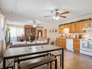 Dining area featuring a wood stove, ceiling fan, light tile patterned floors, and a textured ceiling