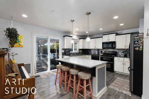 Kitchen featuring backsplash, black appliances, a kitchen bar, decorative light fixtures, and recessed lighting