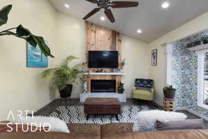 Living room featuring lofted ceiling, wood finished floors, a fireplace, a ceiling fan, and recessed lighting