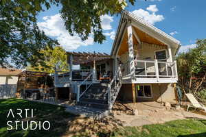 Back of property featuring a patio area, a hot tub, a wooden deck, stairway, and a pergola