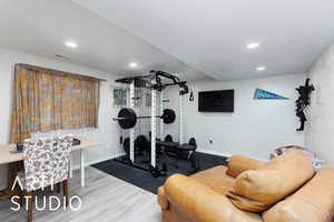 Workout area with wood finished floors and recessed lighting