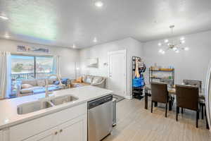 Kitchen with dishwasher, open floor plan, a chandelier, white cabinetry, and light wood finished floors