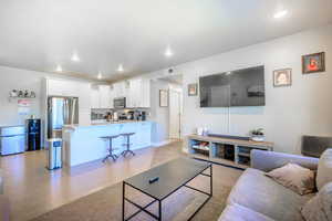 Living area with light wood finished floors and recessed lighting