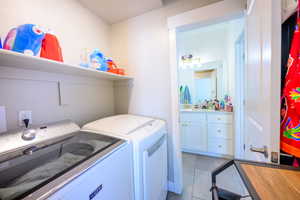 Laundry area featuring light tile patterned floors and separate washer and dryer