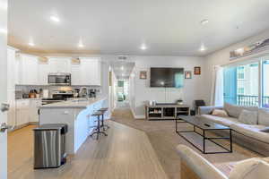 Living room with light wood-type flooring, recessed lighting, and light carpet