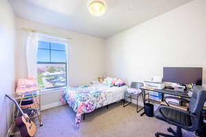 Bedroom with light colored carpet and a desk