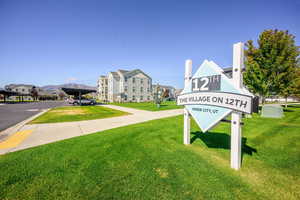 Community / neighborhood sign featuring a lawn and a mountain view