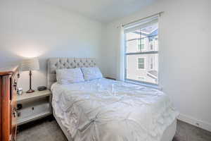 Bedroom with dark carpet and baseboards