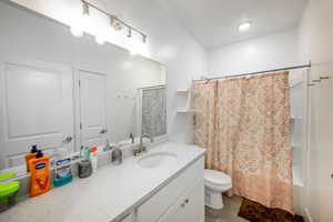 Bathroom featuring shower / bath combination with curtain, vanity, and light tile patterned floors