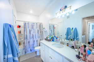 Full bathroom featuring light tile patterned floors, shower / bath combo with shower curtain, and vanity