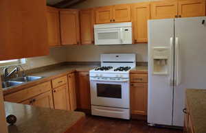 Kitchen with white appliances and dark wood-type flooring