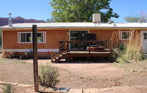 Rear view of house featuring a metal roof, a wooden deck, and heating fuel