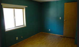 Unfurnished room with wood finished floors and baseboards