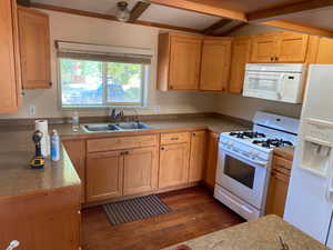 Kitchen featuring white appliances, dark wood finished floors, light countertops, and light brown cabinets